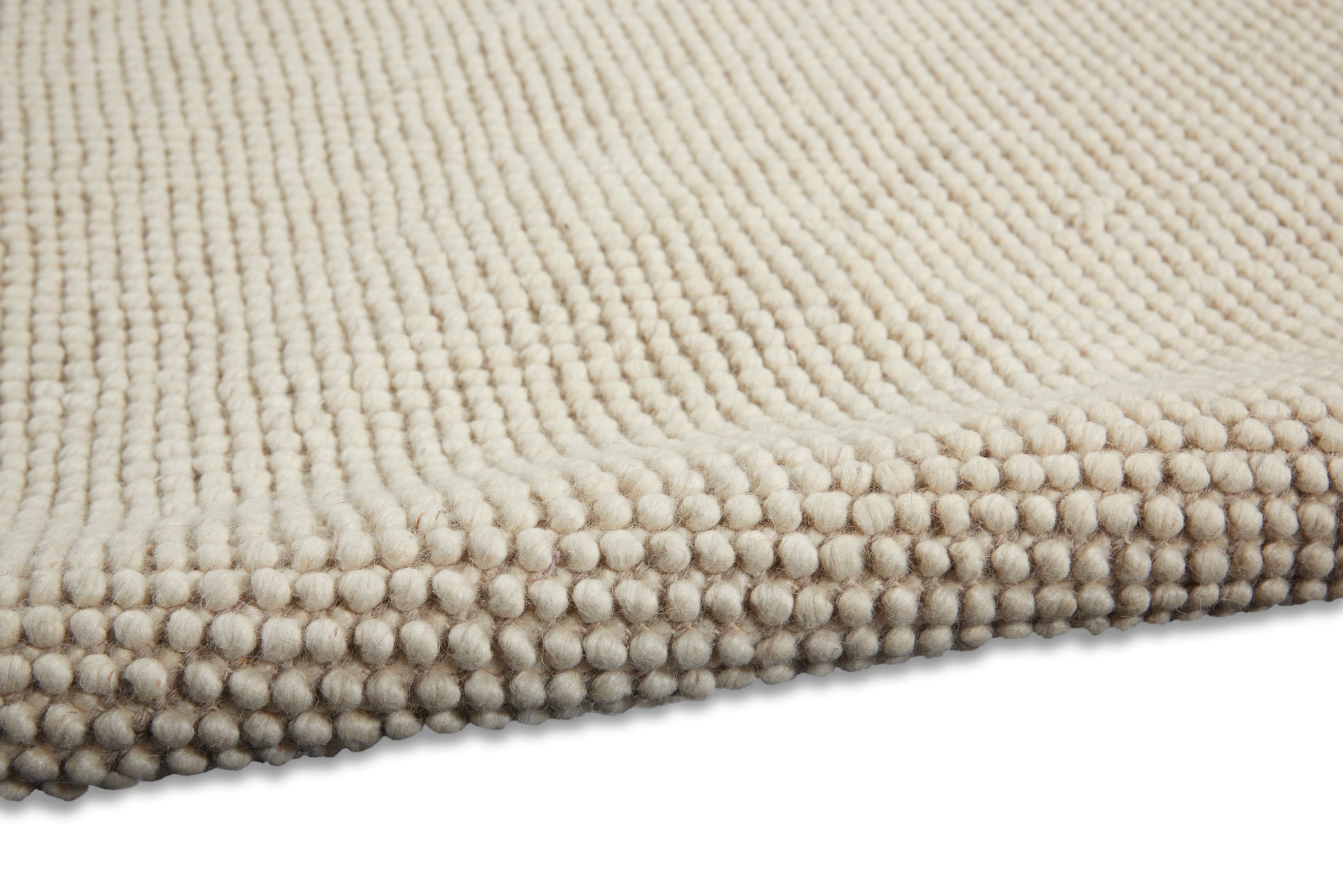 Beige loop-pile rug close-up with dense textured surface and chunky knotted edge.