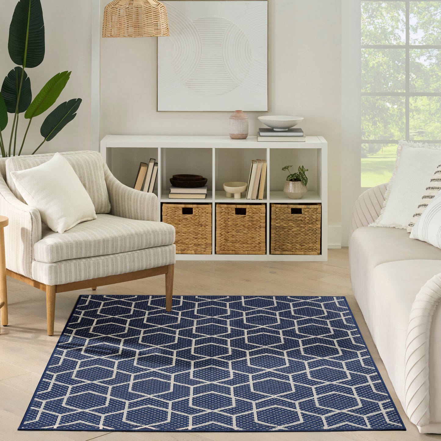 Neutral living room with navy geometric rug (white lattice), beige upholstered chair, white cube shelf with woven baskets and plants.