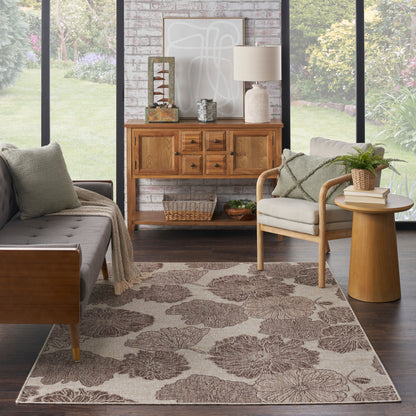 Living room with grey tufted sofa, mid-century armchair, beige floral rug, wooden console and brick wall.