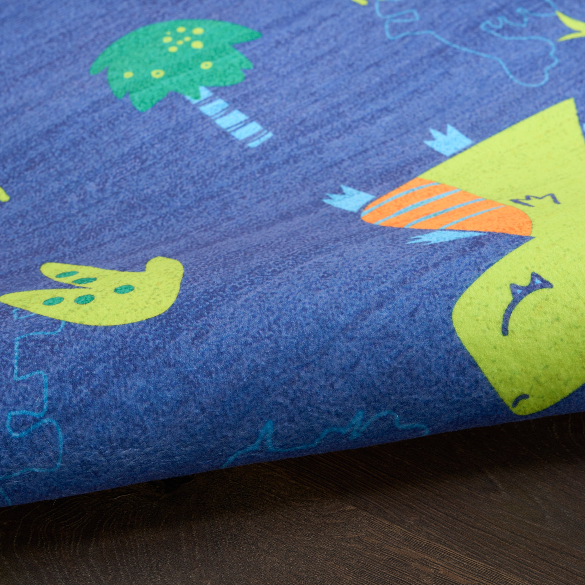 Blue kids' rug with lime-green dinosaur, palm tree and bird prints, and orange striped details