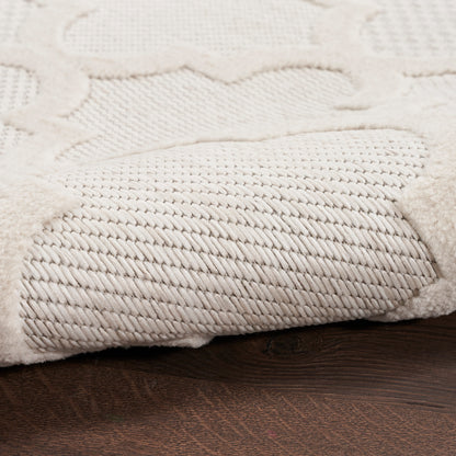 Cream textured rug with a dense twisted pile and raised scroll pattern on a dark wood floor.