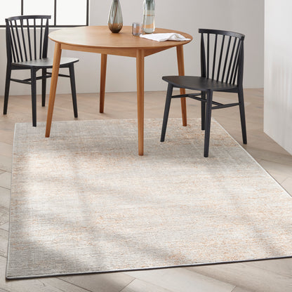 Round natural wood dining table with tapered legs, paired with black spindle-back chairs on a beige textured rug.