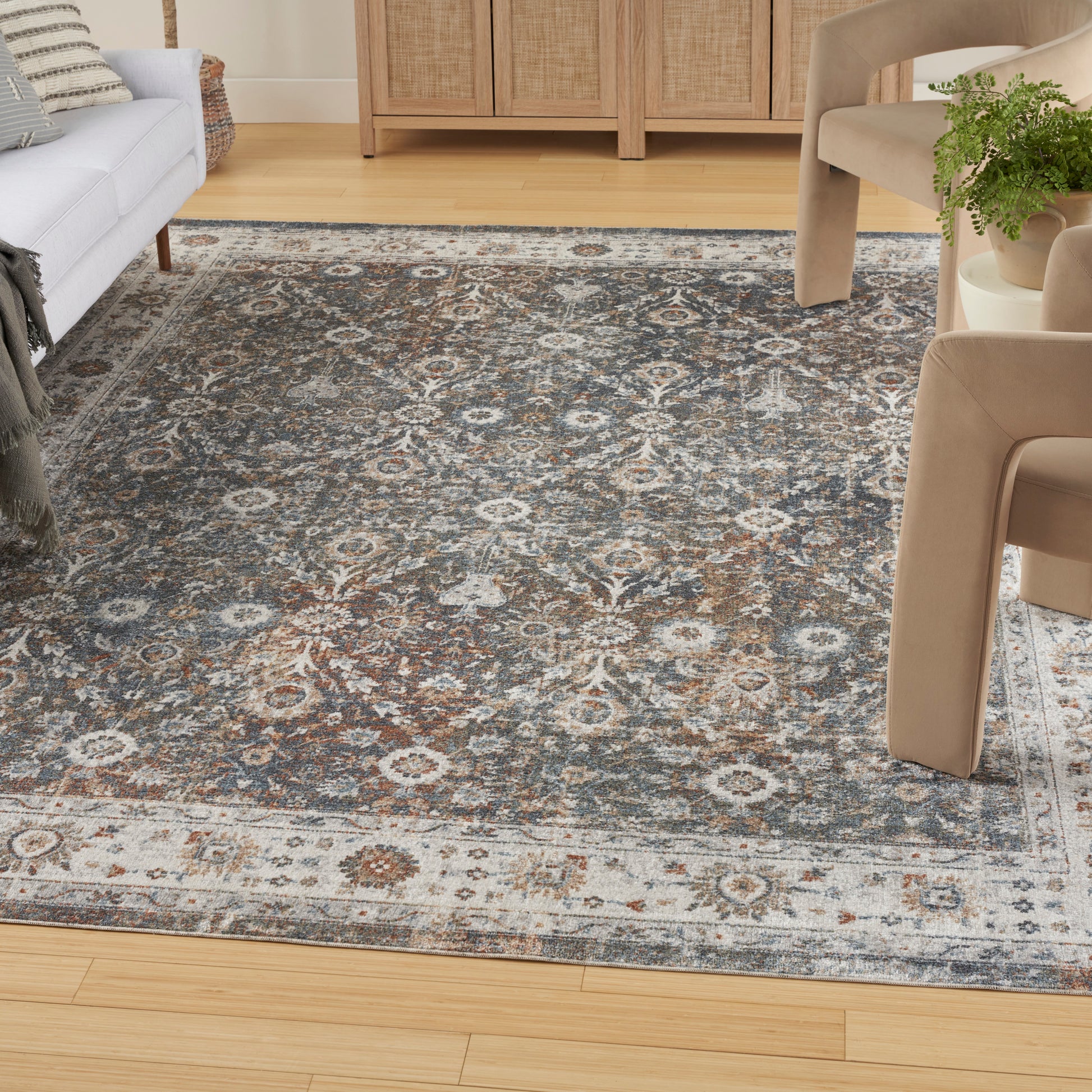 Traditional blue-gray oriental area rug with cream medallions in a living room with beige chairs and wooden floor.