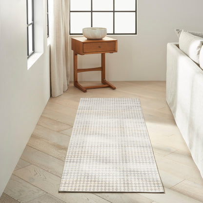 Light gray and white geometric runner rug on pale wood floor beside a wooden side table topped with a ceramic bowl.
