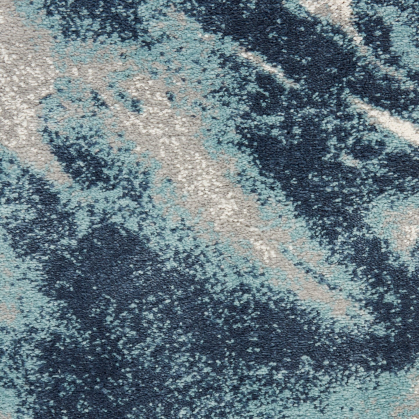 Abstract blue-toned area rug with navy, teal and beige marbled pattern and soft textured pile.