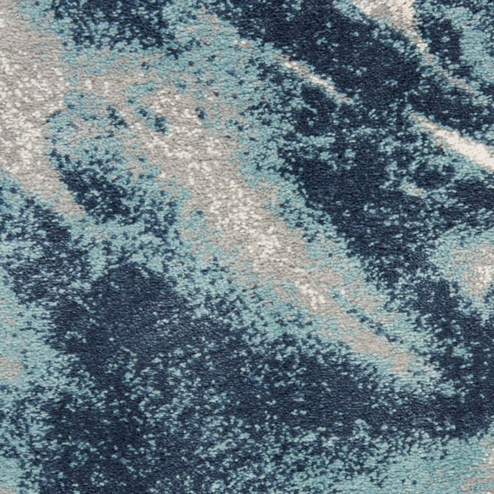 Abstract blue-toned area rug with navy, teal and beige marbled pattern and soft textured pile.