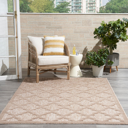 Modern 5' x 7' tan geometric rug, with wicker outdoor armchair, beige cushions, a yellow striped pillow, side table & potted plants.