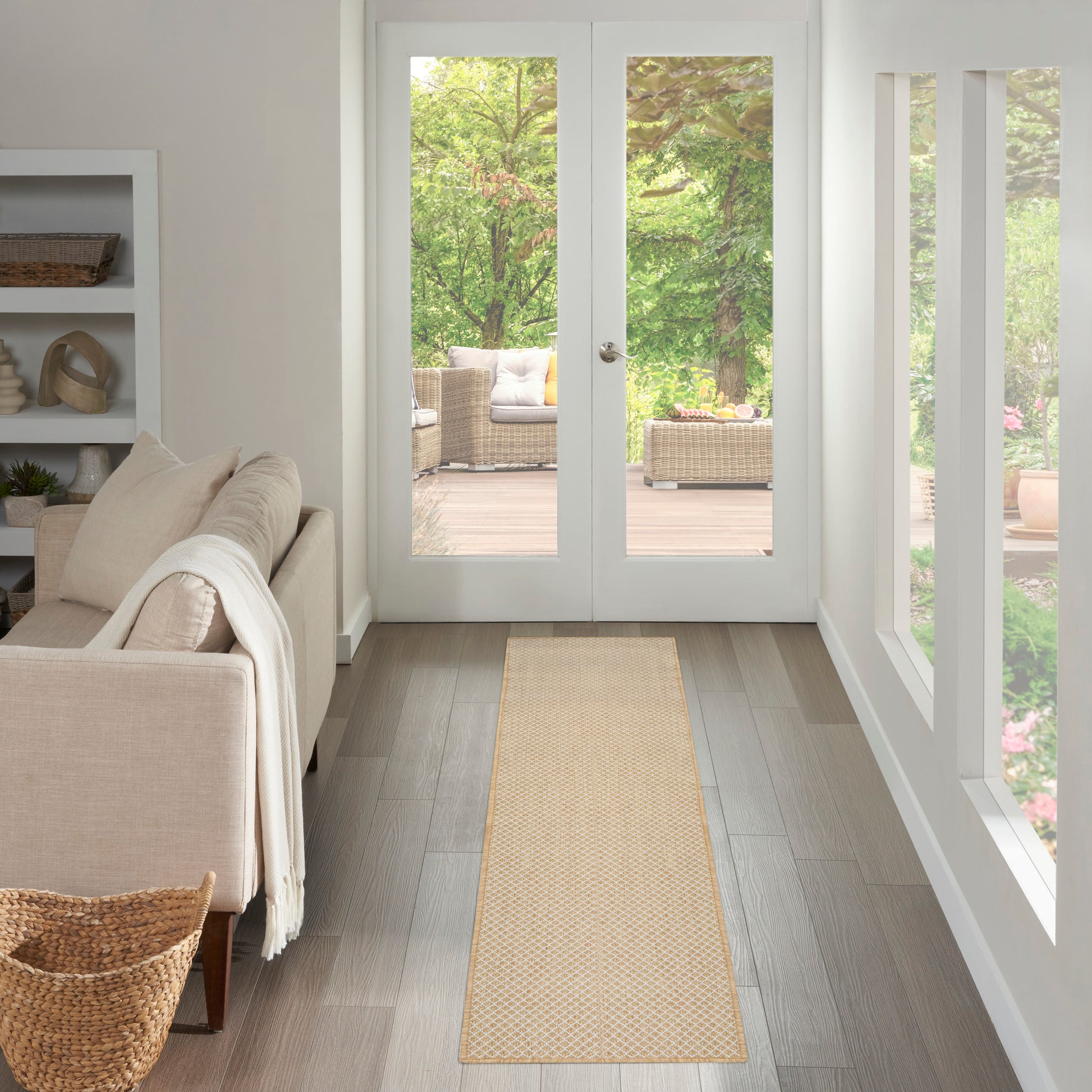 Beige woven runner rug on light wood floor in a bright living room with white walls, sofa, basket, and glass doors to outdoor seating.