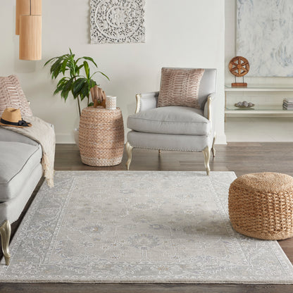 Vintage patterned rug (5' x 8') in a boho living room with a light gray armchair, woven rattan pouf, and natural wicker side table.
