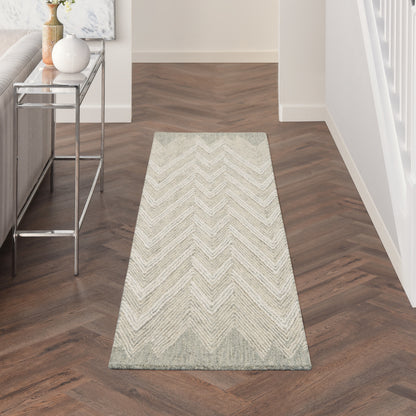 Long light beige chevron rug runner on dark wood herringbone floor; modern entryway with chrome console on left.