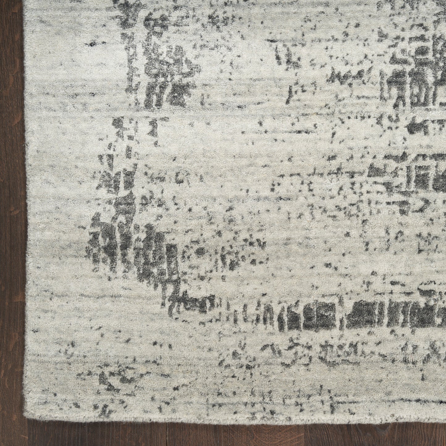 Distressed cream and gray area rug with subtle abstract pattern and dark brown left-edge border.