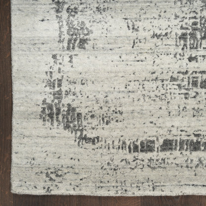 Distressed cream and gray area rug with subtle abstract pattern and dark brown left-edge border.