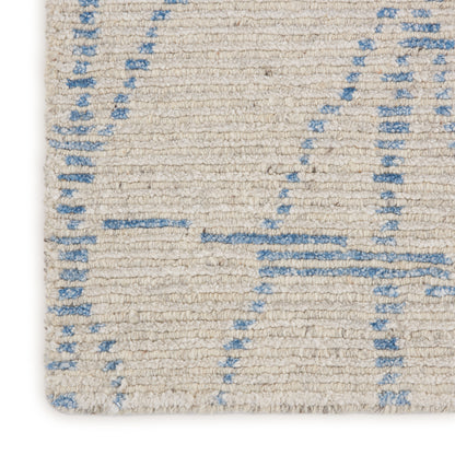 Close-up of cream woven rug with light blue geometric lines; textured flat-weave, neutral casual style.