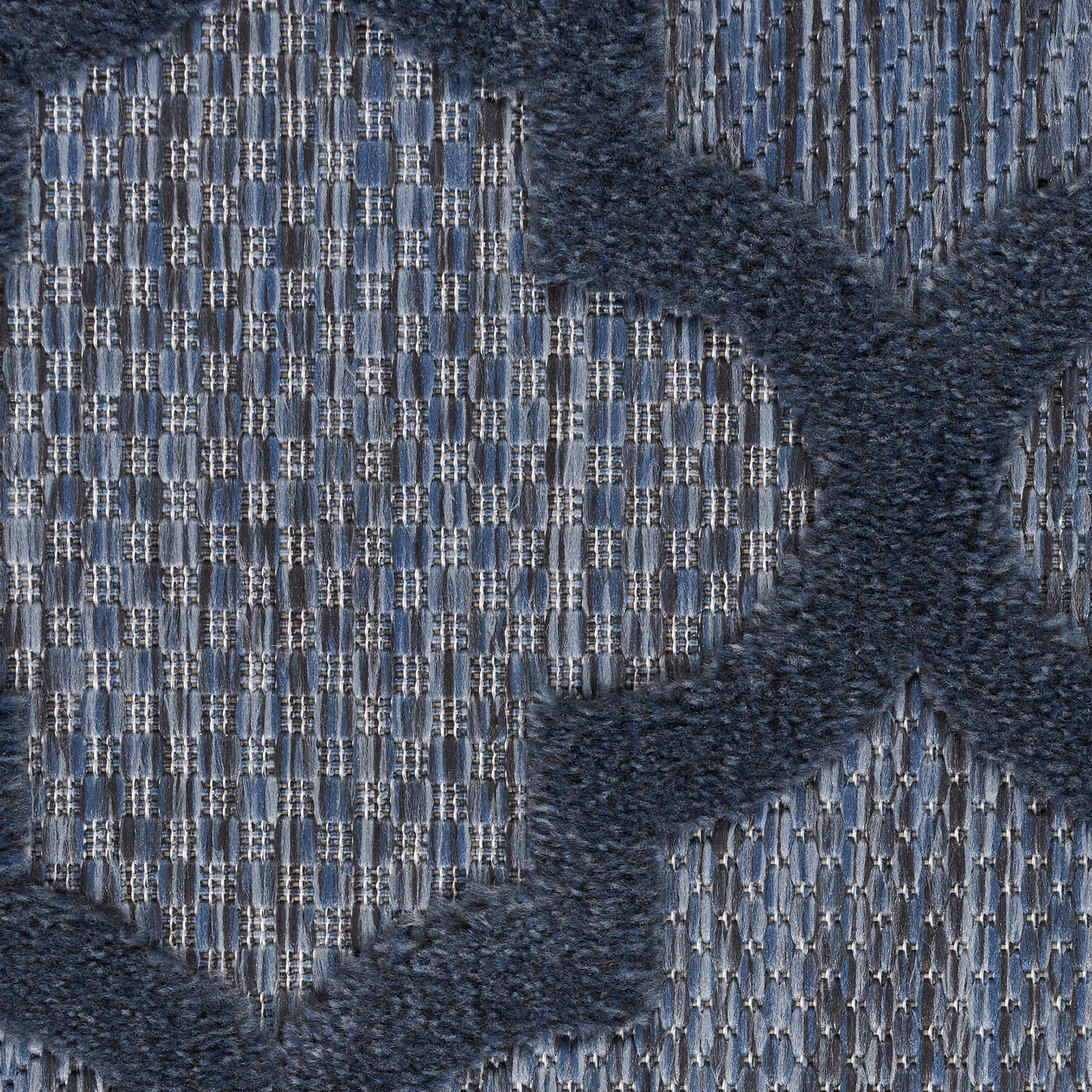 Close-up of blue woven rug with a light grid pattern and dark navy plush cross motif.