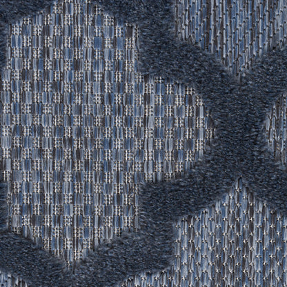 Close-up of blue woven rug with a light grid pattern and dark navy plush cross motif.