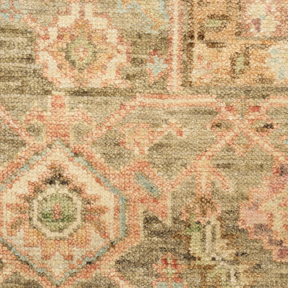 Close-up of a textured oriental rug with beige, pink, and sage green geometric motifs.