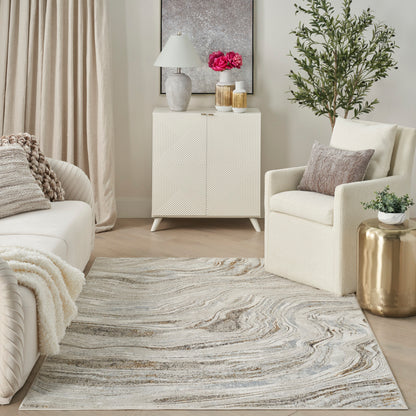Cream living room with beige sofa, knit throw, geometric textured cabinet, swirl rug, gold side table, tall plant.