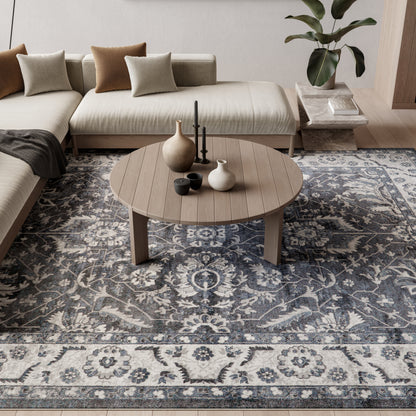 Ornate blue-gray rug in a living room with a round wooden coffee table, ceramic vases, and a beige sectional sofa with neutral cushions.
