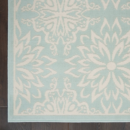 Light blue area rug with white damask floral pattern and pale blue border on dark wood floor.