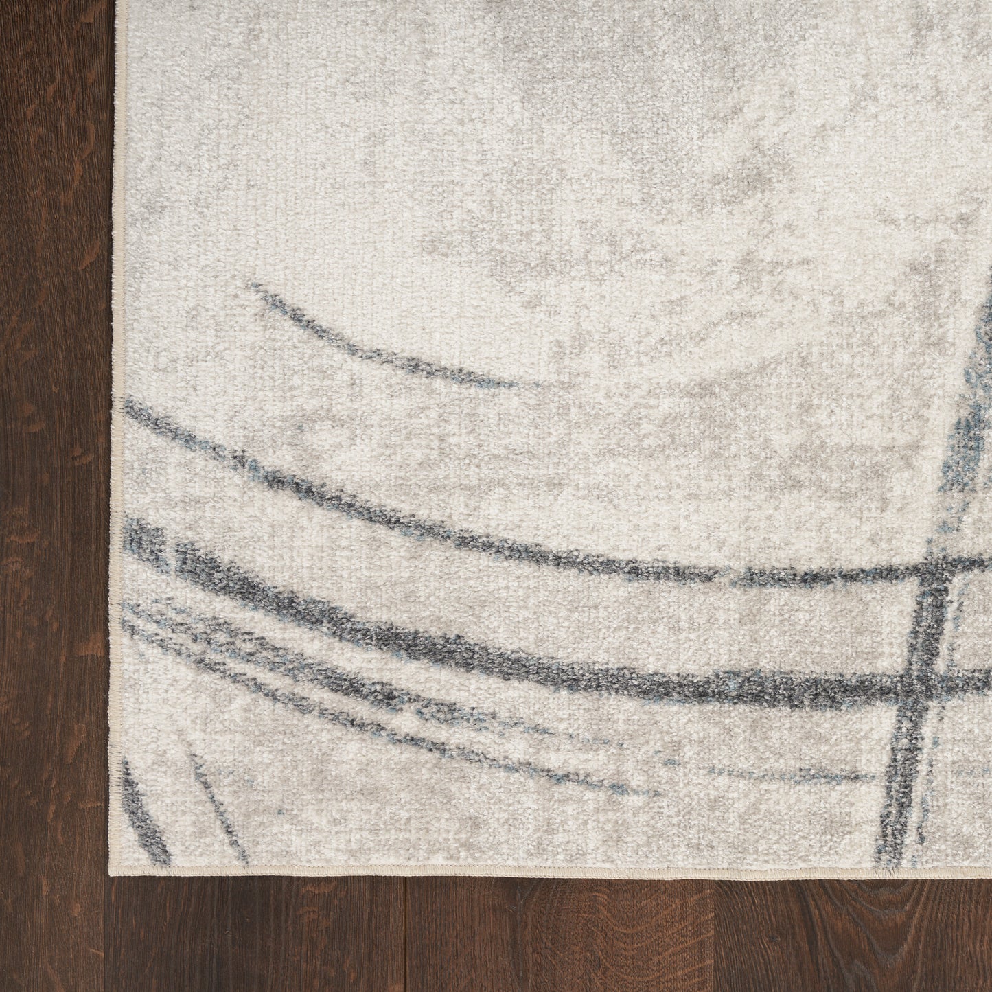 Rectangular cream rug with gray curved lines in a modern abstract pattern on dark wood floor.