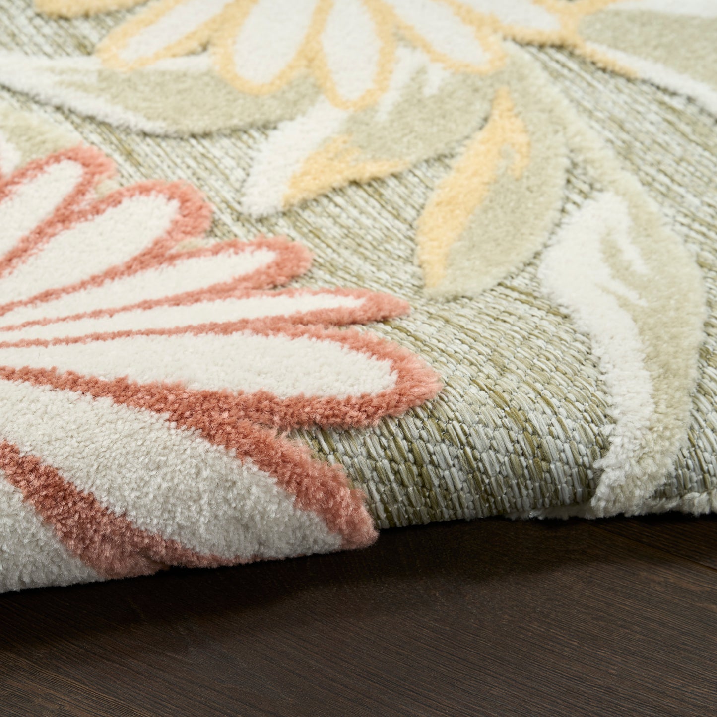 Close-up of pastel floral rug with pink petal motif, yellow and green leaves, thick plush pile.