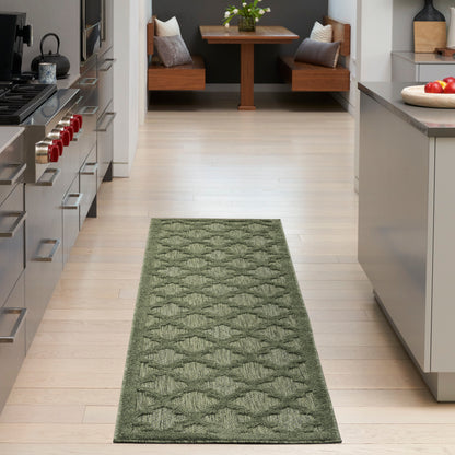 Green diamond-pattern runner rug on light hardwood kitchen floor in a modern kitchen with stainless appliances.