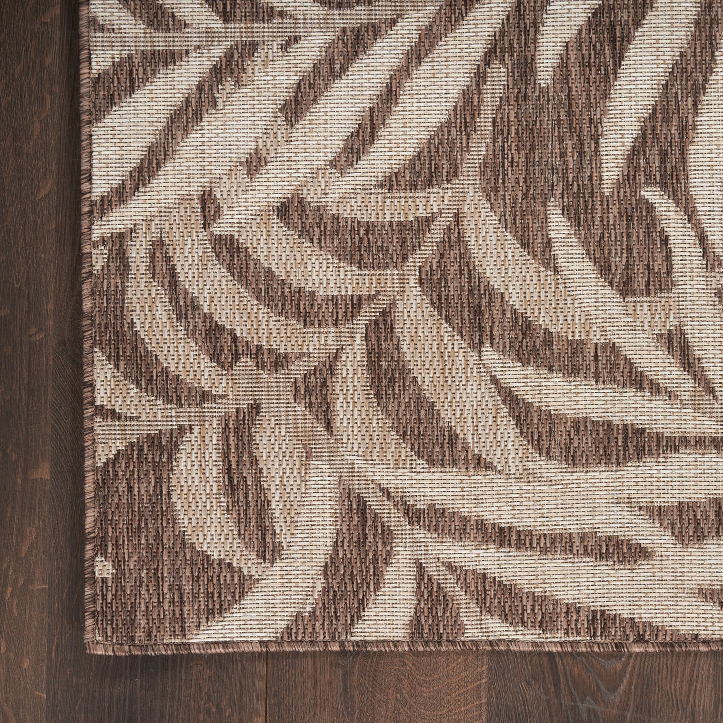 Brown & beige leaf-pattern area rug with a woven texture on a dark wood floor; rectangular, modern botanical style.