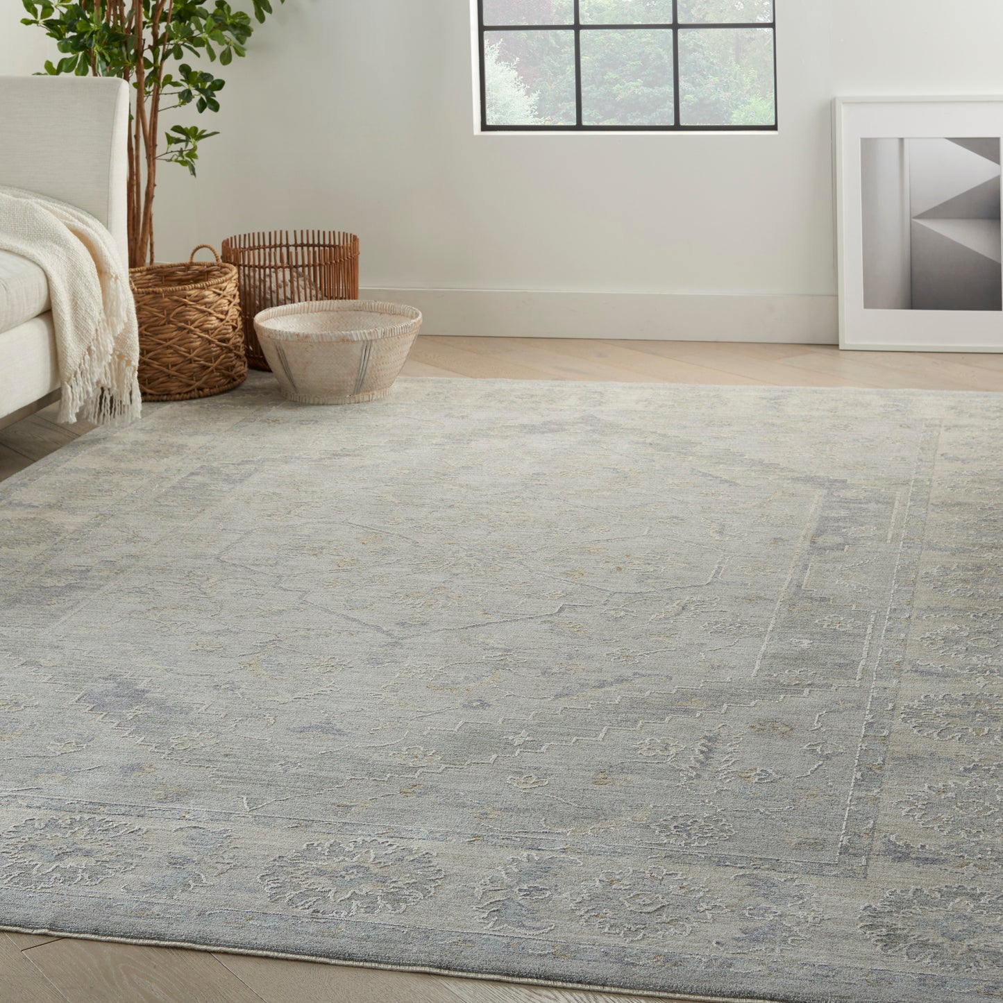 Blue-gray patterned rectangular area rug with subtle floral motifs in a bright living room.
