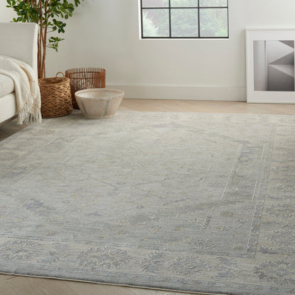 Blue-gray patterned rectangular area rug with subtle floral motifs in a bright living room.