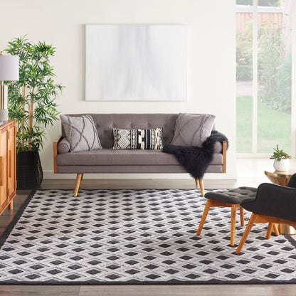 Cozy living room with gray mid-century sofa, wooden legs, geometric cushions, black faux-fur throw, and a diamond rug.