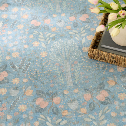 Blue floral patterned rug with pink flowers & pale leaves; wicker tray with vase of tulips & books in corner.