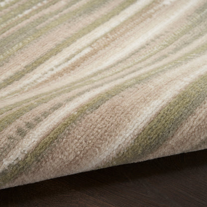 Soft striped area rug in beige, sage green, and olive tones with a folded edge on dark wood floor.