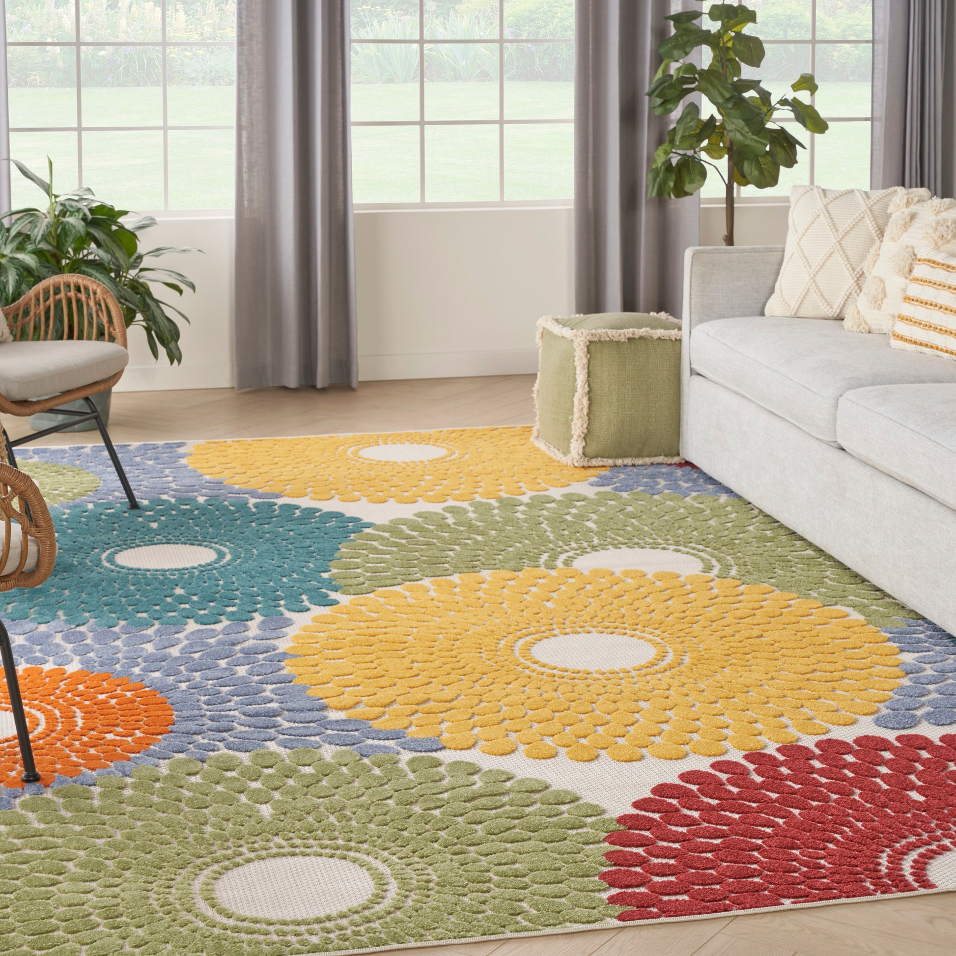 Multicolor circular rosette area rug in yellow, blue, green, orange, and red in a bright living room with a gray sofa.