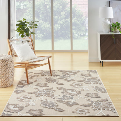 Beige floral area rug with gray vines in a bright living room; light wood floor, wicker chair, and modern cabinet.