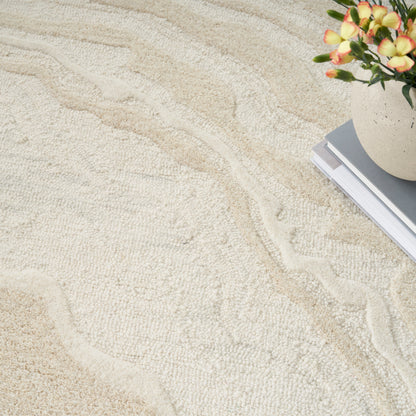 Cream textured rug with subtle wavy pattern; corner features a vase of flowers and a stack of books.