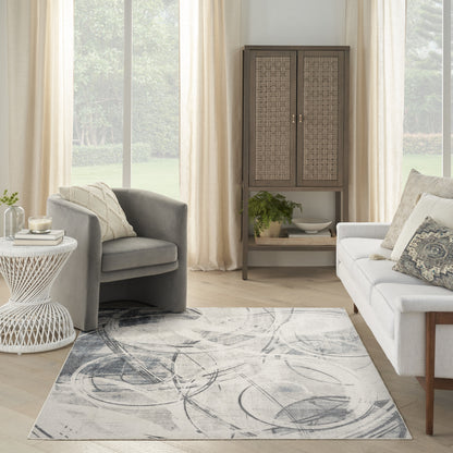 Neutral living room with gray fabric chairs, white sofa, beige curtains, a woven-rattan cabinet, and an abstract gray rug.