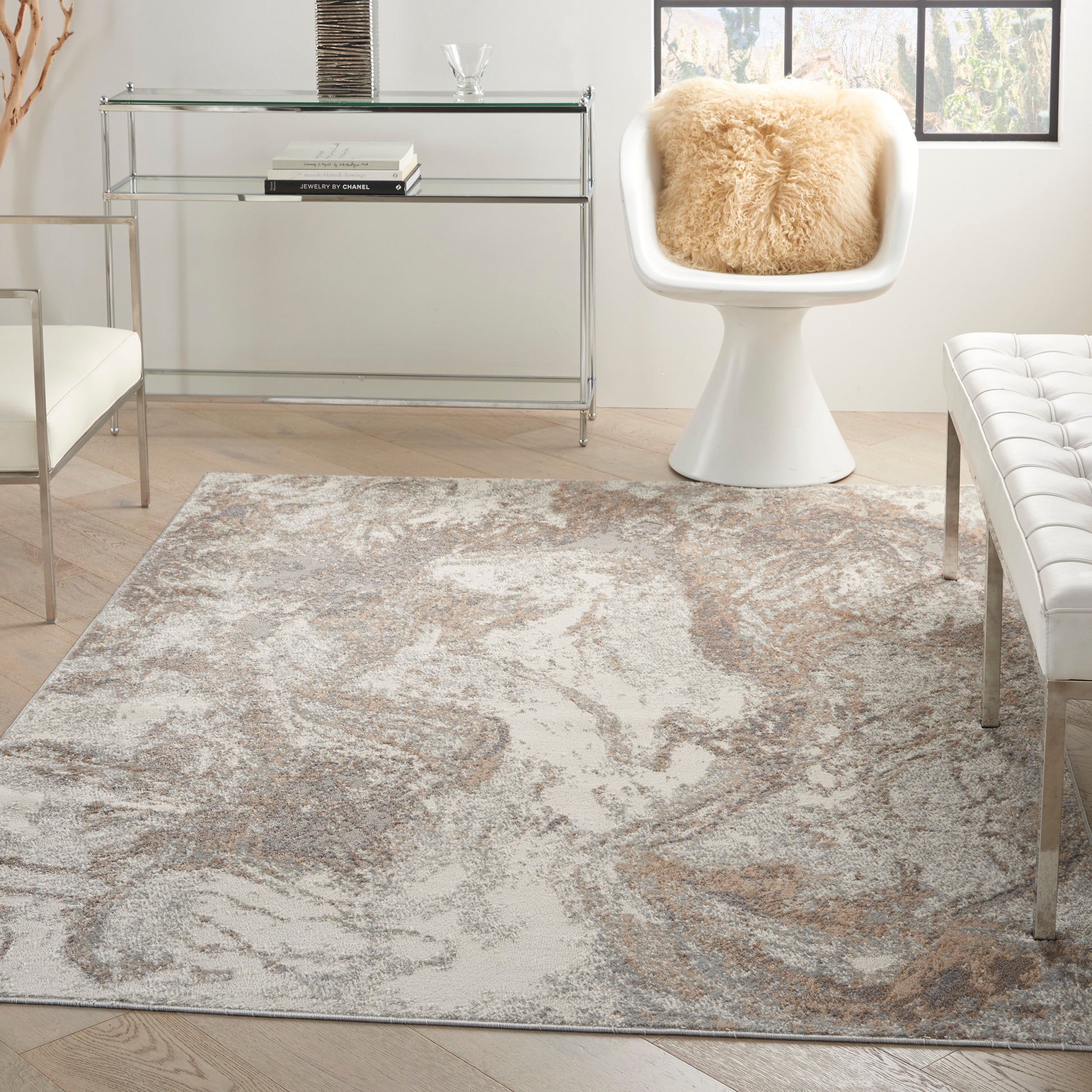 Modern living room with abstract beige-gray rug, white tulip chair with shearling cushion, and glass console table.