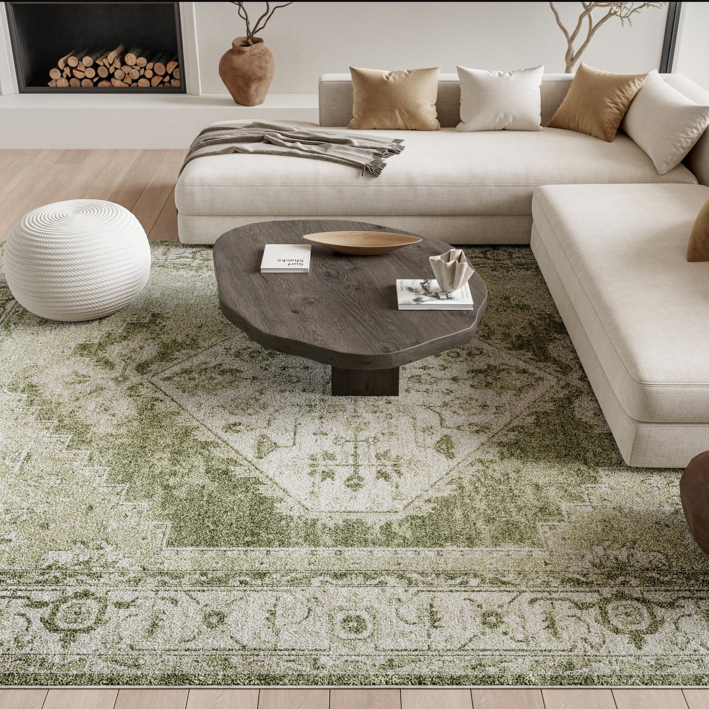 Neutral living room with beige sectional, dark wooden oval coffee table, white knitted pouf, and green vintage-pattern rug.
