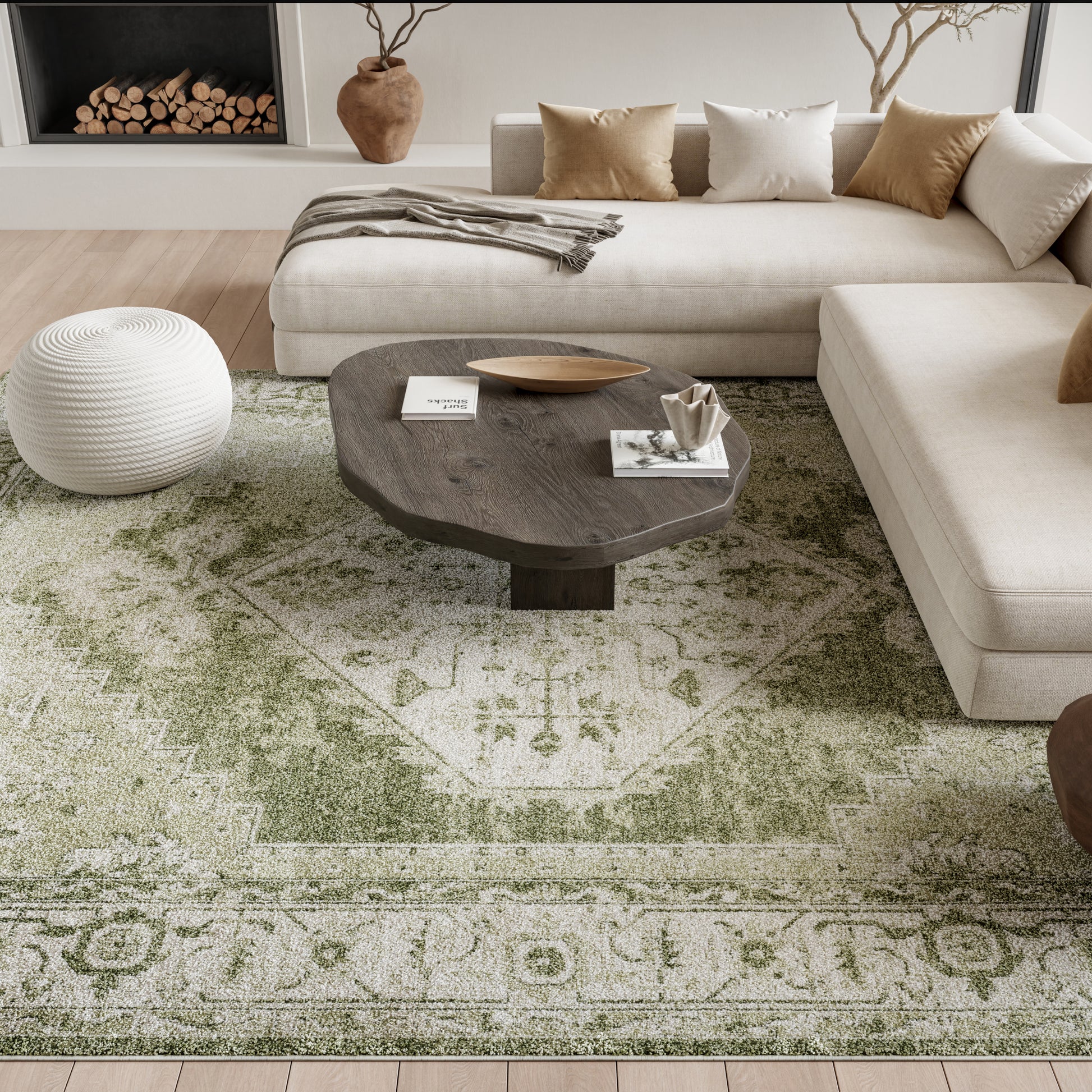 Neutral living room with beige sectional, dark wooden oval coffee table, white knitted pouf, and green vintage-pattern rug.