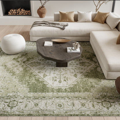 Neutral living room with beige sectional, dark wooden oval coffee table, white knitted pouf, and green vintage-pattern rug.