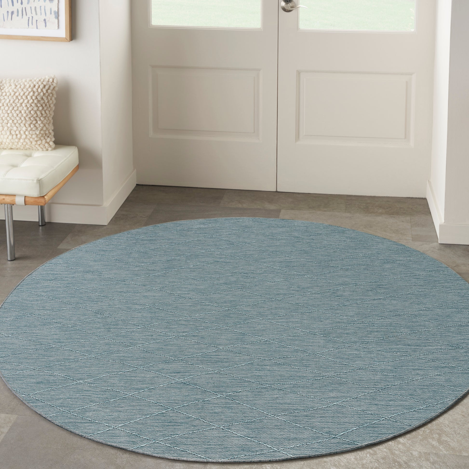 Round blue textured rug with diagonal diamond pattern, ideal entryway decor on gray tile near white doors.