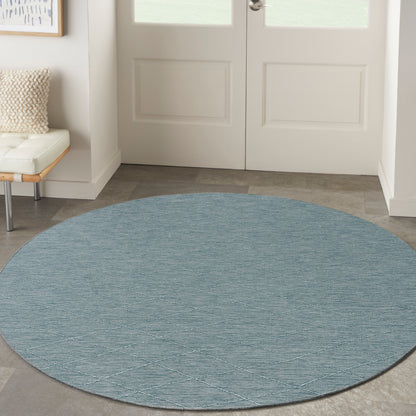 Round blue textured rug with diagonal diamond pattern, ideal entryway decor on gray tile near white doors.