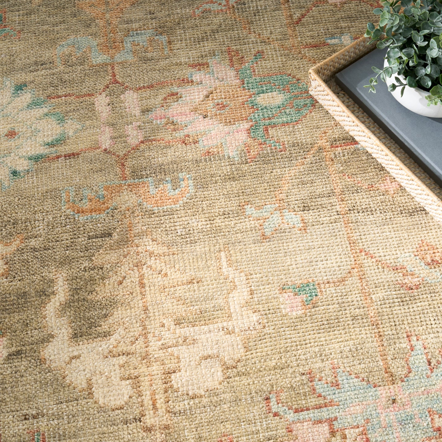 Beige vintage-inspired woven area rug with subtle peach, teal and light blue geometric motifs; distressed texture.