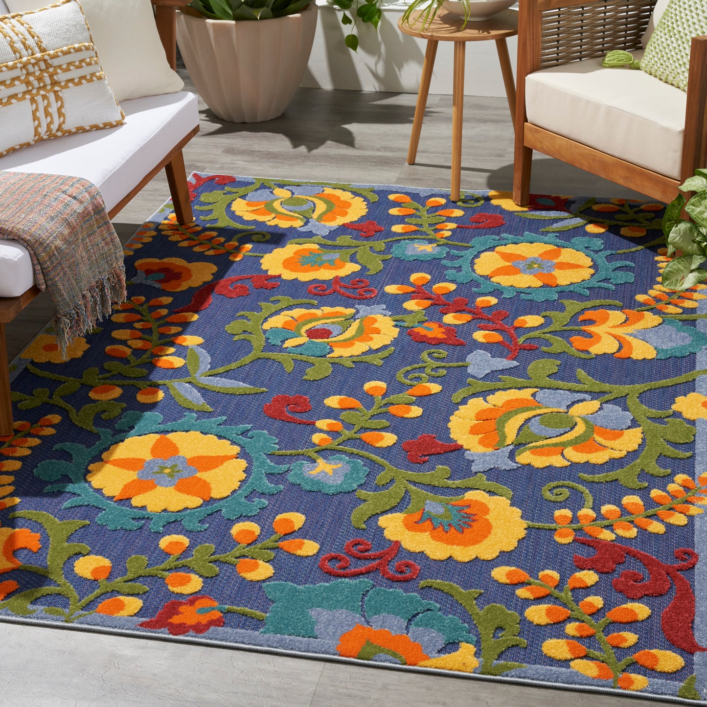Vibrant floral outdoor area rug with blue background, yellow/orange blossoms and green vines.