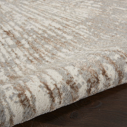 Soft plush rug in cream and taupe with abstract wavy pattern on dark wood floor.