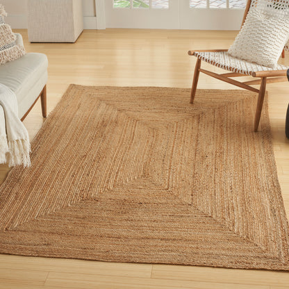 Natural jute area rug with concentric rectangle weave in a bright living room; tan beige woven texture.