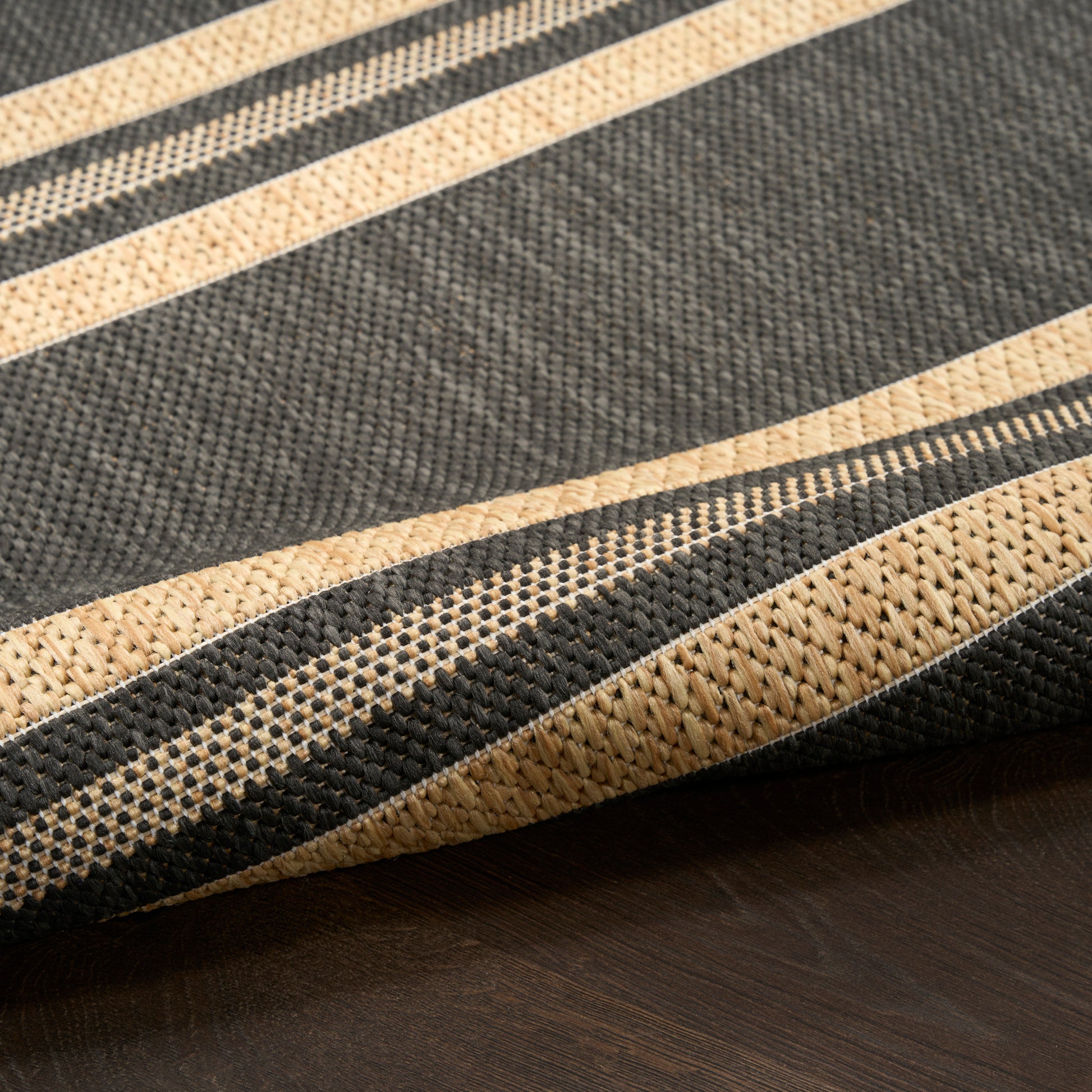 Woven stripe runner in charcoal black and natural beige with textured bands, modern rustic floor decor.