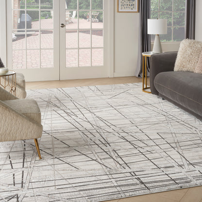 Modern living room rug with light gray abstract geometric lines on hardwood floor, beige chair and gray sofa.