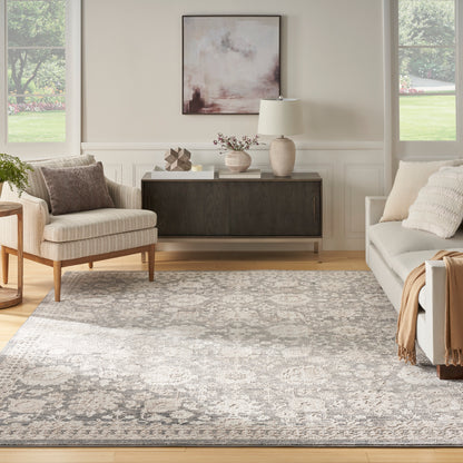 Neutral living room with beige armchair, gray sofa, a patterned rug (6' x 9'), dark wood sideboard, abstract art & lamp.