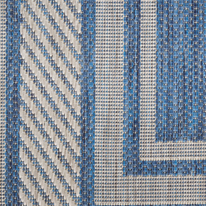 Blue and beige woven rug with diagonal stripes and bordered geometric panels in a textured cotton blend.